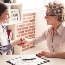 Dos mujeres se dan la mano mientras están sentadas en una mesa.
