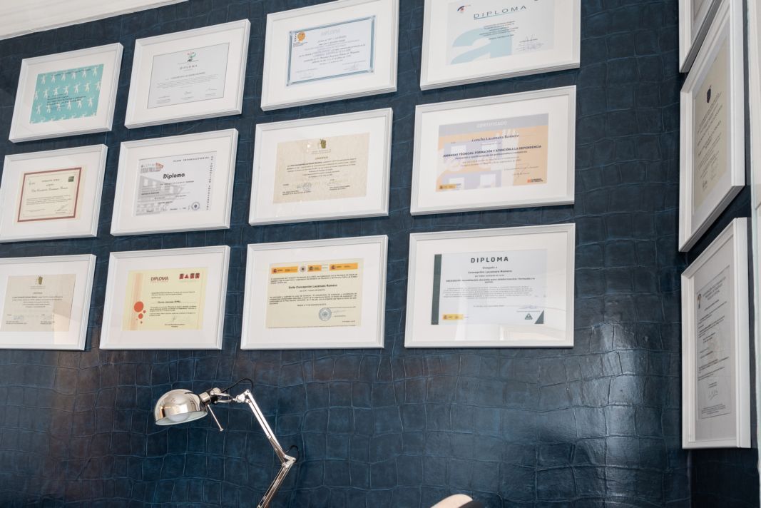 Una persona está sentada en un escritorio frente a una pared de cuadros enmarcados.