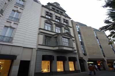 Ein großes Gebäude mit vielen Fenstern und Menschen, die davor gehen.