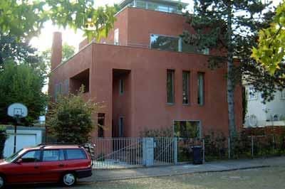 Ein rotes Auto parkt vor einem großen roten Gebäude.