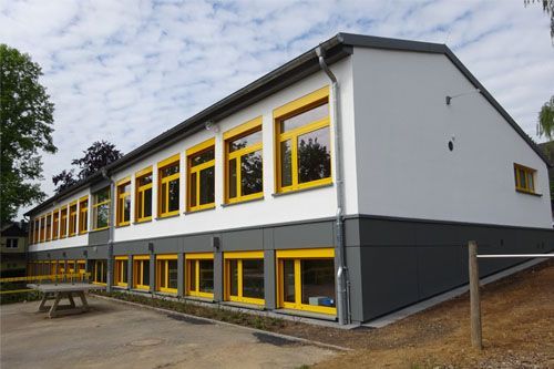 Ein großes Gebäude mit gelben Fenstern und einem Picknicktisch davor