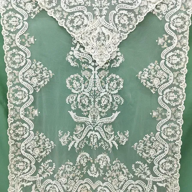 Un camino de mesa de encaje blanco con un fondo verde.
