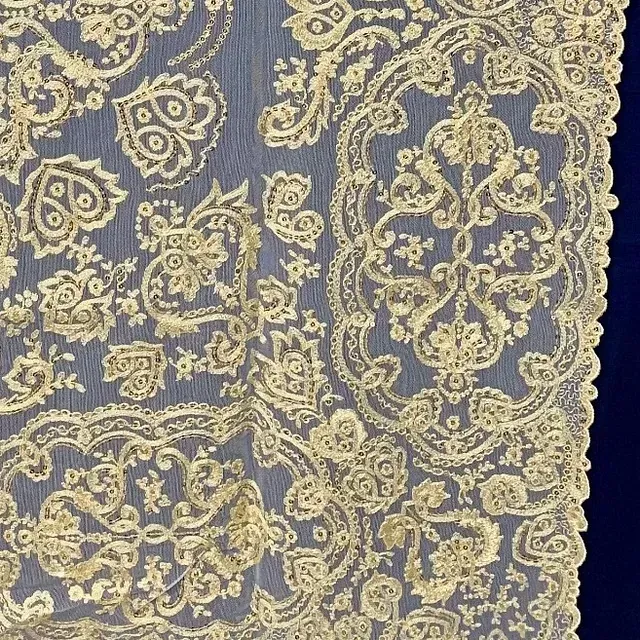 Un primer plano de una tela de encaje dorado sobre un fondo azul.