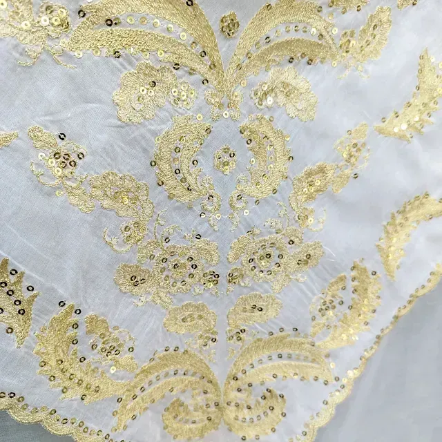Un primer plano de una tela blanca con lentejuelas doradas.