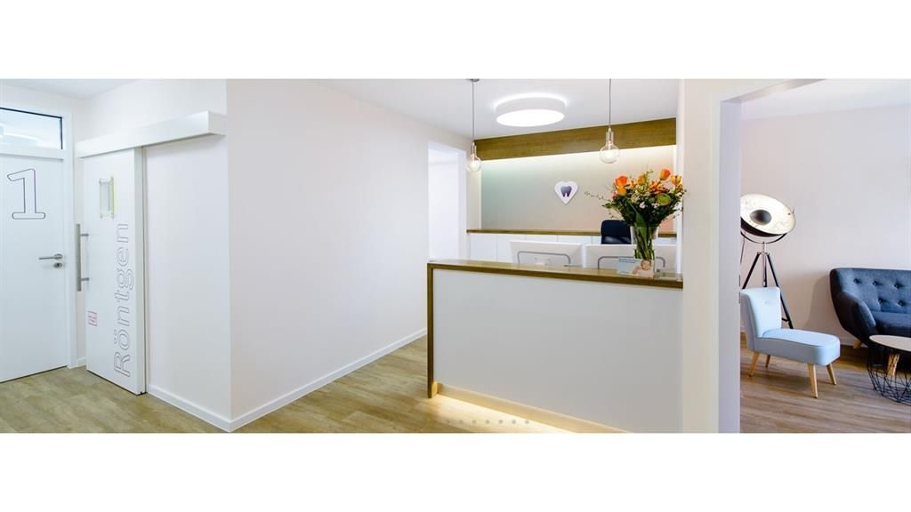 Im Wartezimmer neben der Rezeption steht eine Couch.