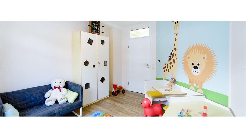 Ein Kind spielt in einem Zimmer mit einem Löwen und einer Giraffe an der Wand.