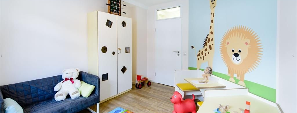 Ein Kind spielt in einem Zimmer mit einem Löwen und einer Giraffe an der Wand.