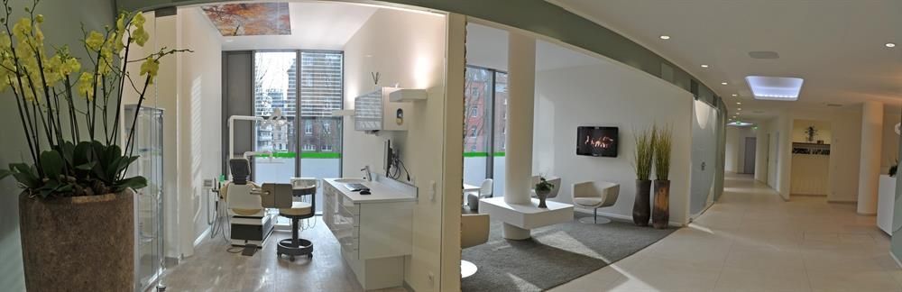 Ein Panoramablick auf eine Zahnarztpraxis mit einem Schreibtisch und Stühlen.