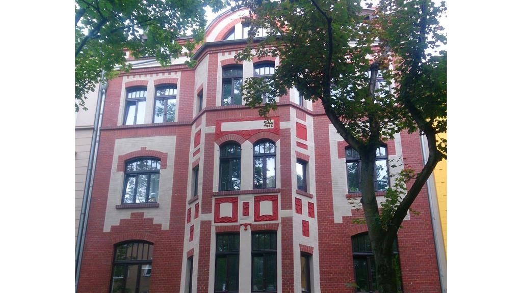 Ein rot-weißes Backsteingebäude mit einem Baum davor