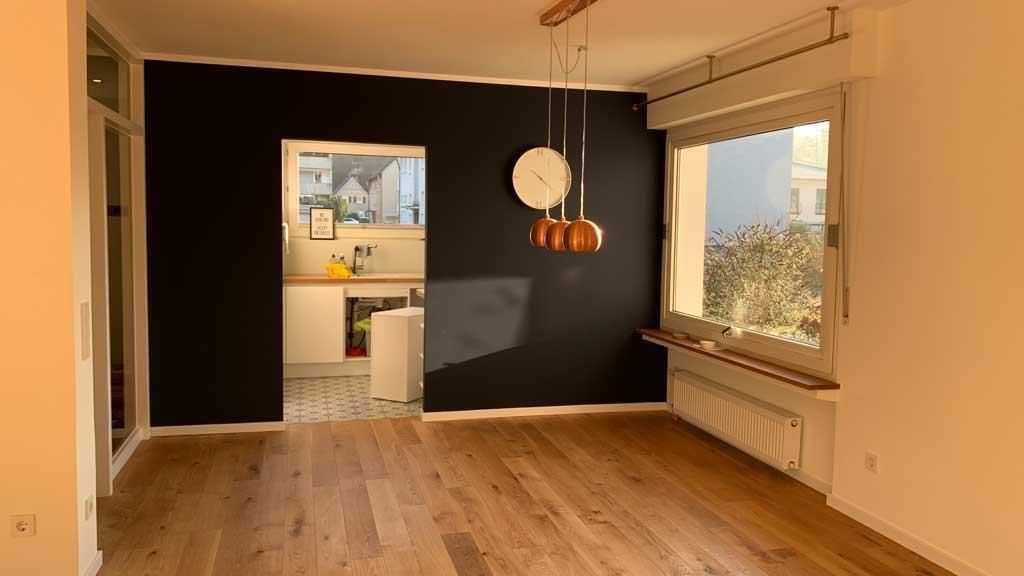 Ein leeres Wohnzimmer mit Hartholzböden und einer schwarzen Wand