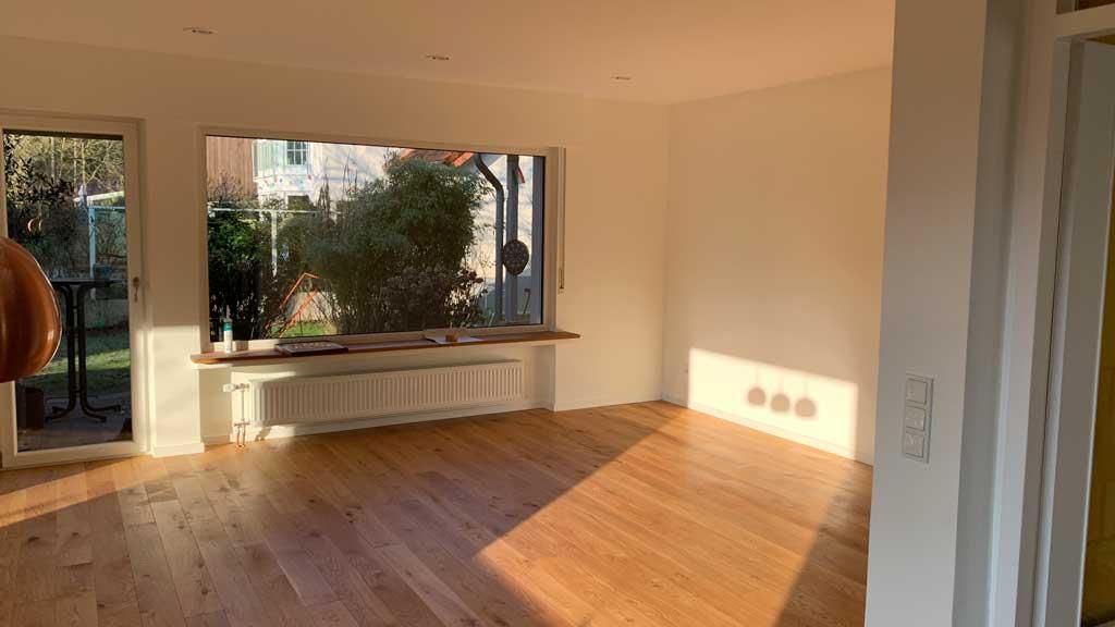 Ein leeres Wohnzimmer mit Hartholzböden und einem großen Fenster.