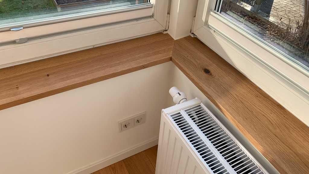 Ein Heizkörper steht auf einer Fensterbank neben einem Fenster.