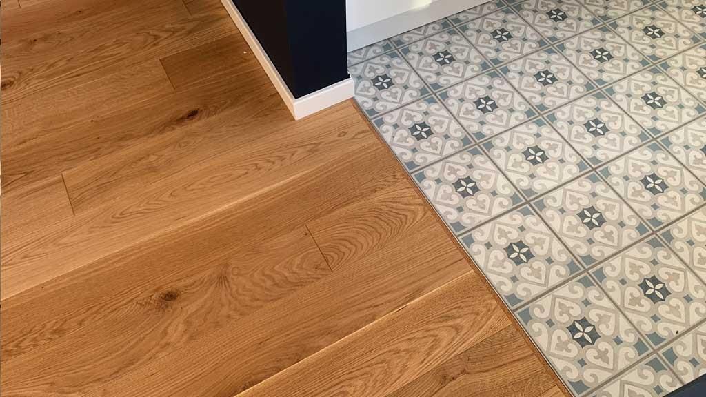 Ein Holzboden neben einem Fliesenboden in einer Küche.