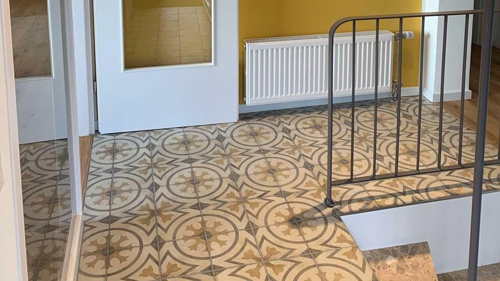 Eine Treppe mit gemustertem Fliesenboden und Metallgeländer