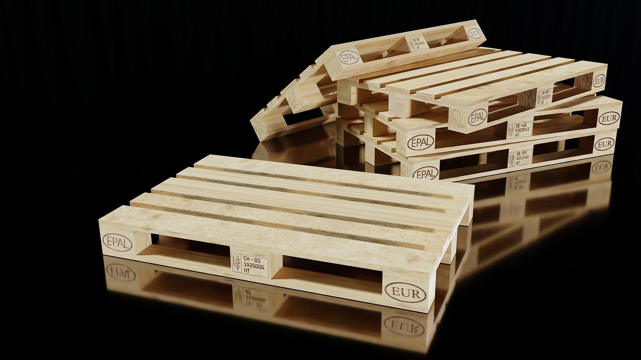Tres paletas de madera están apiladas una encima de otra sobre una superficie negra.