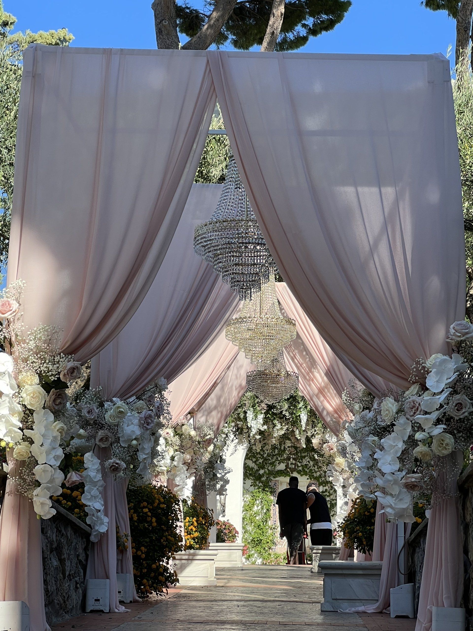 Allée décorée de draps roses et de composition florale blanche