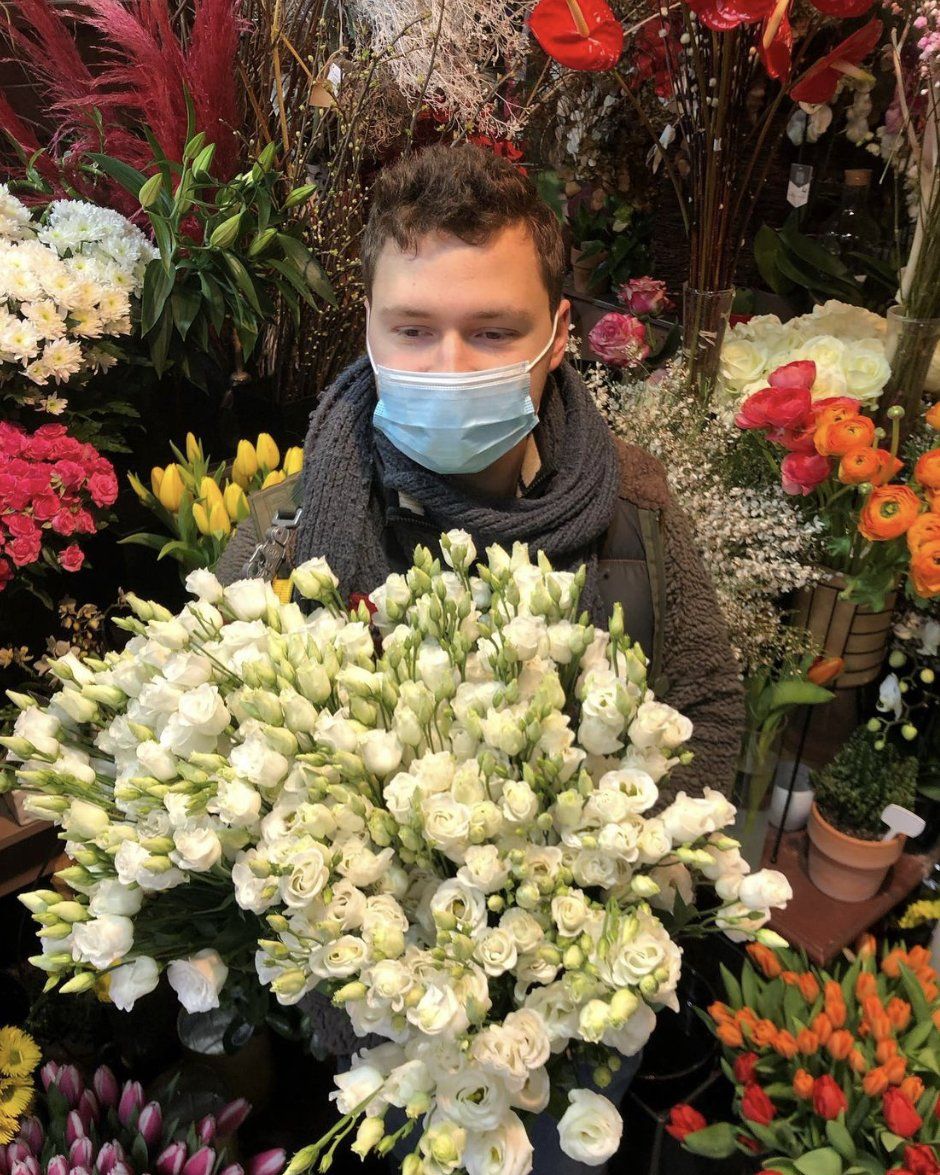 Fleuriste masqué avec un bouquet de fleurs blanches