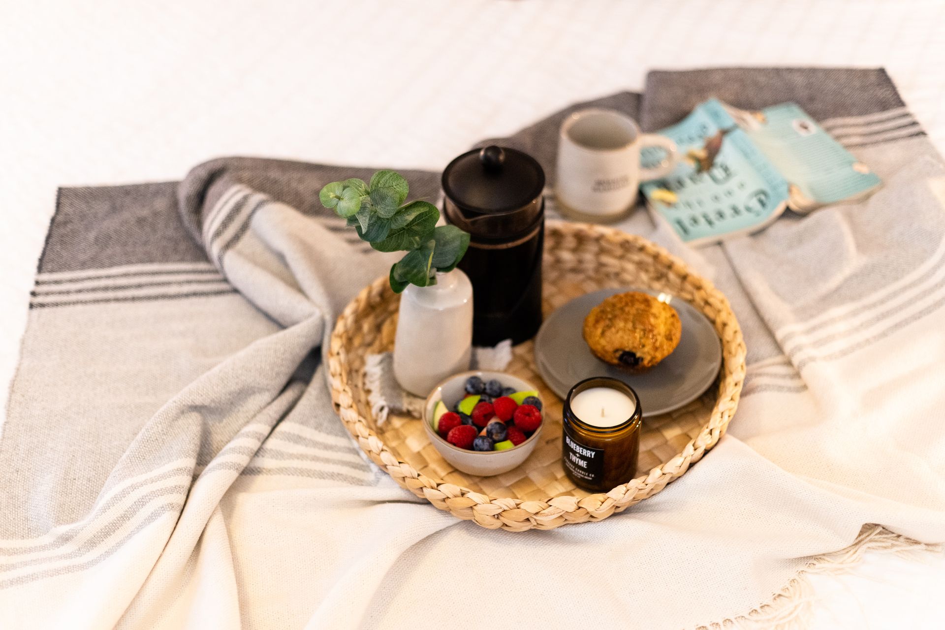 a wicker tray filled with food and a book on a bed .