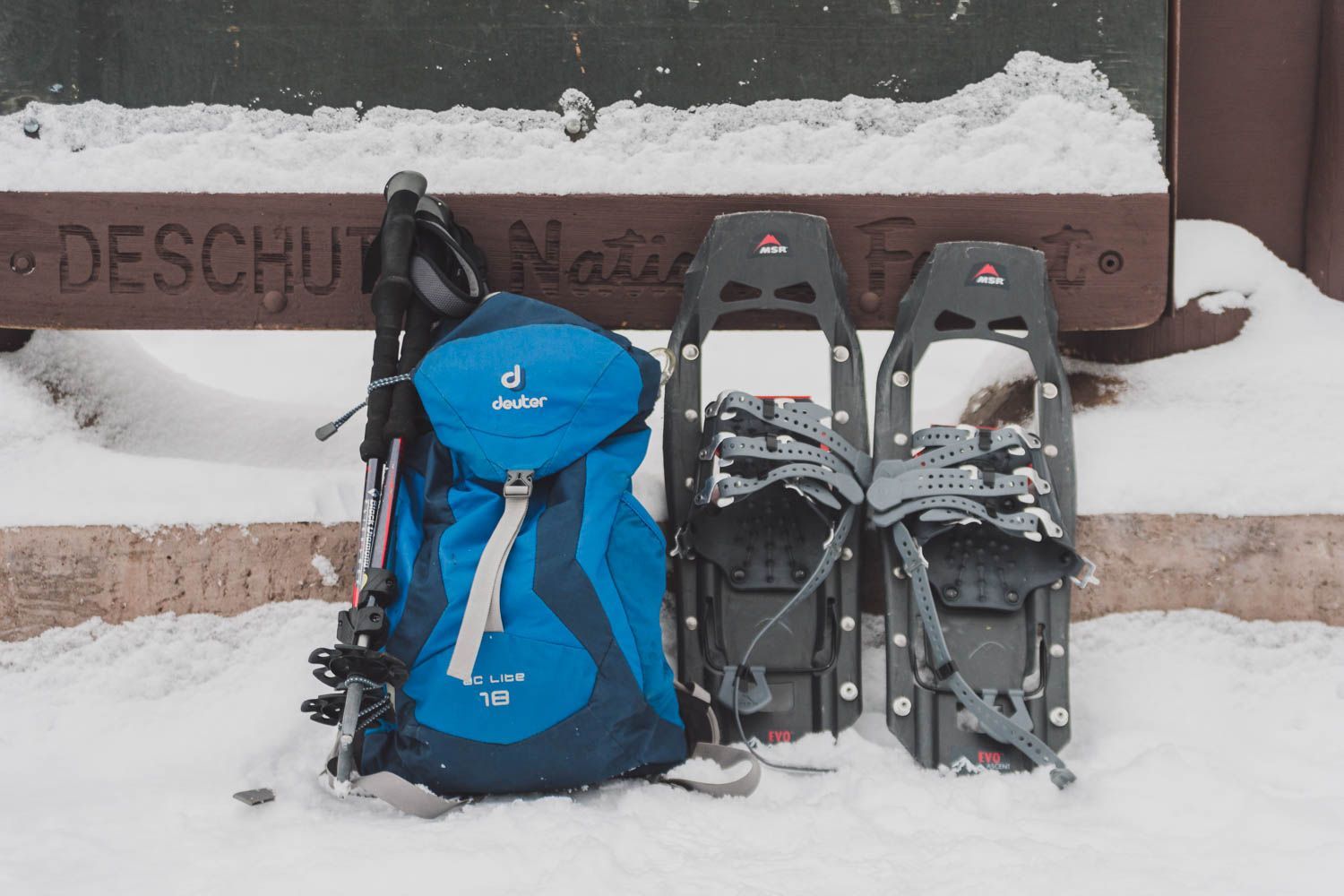 backpack and snowshoes sitting on the snow in front of a Deschutes National Forest sign to represent the best dog friendly snowshoe trails in Central Oregon