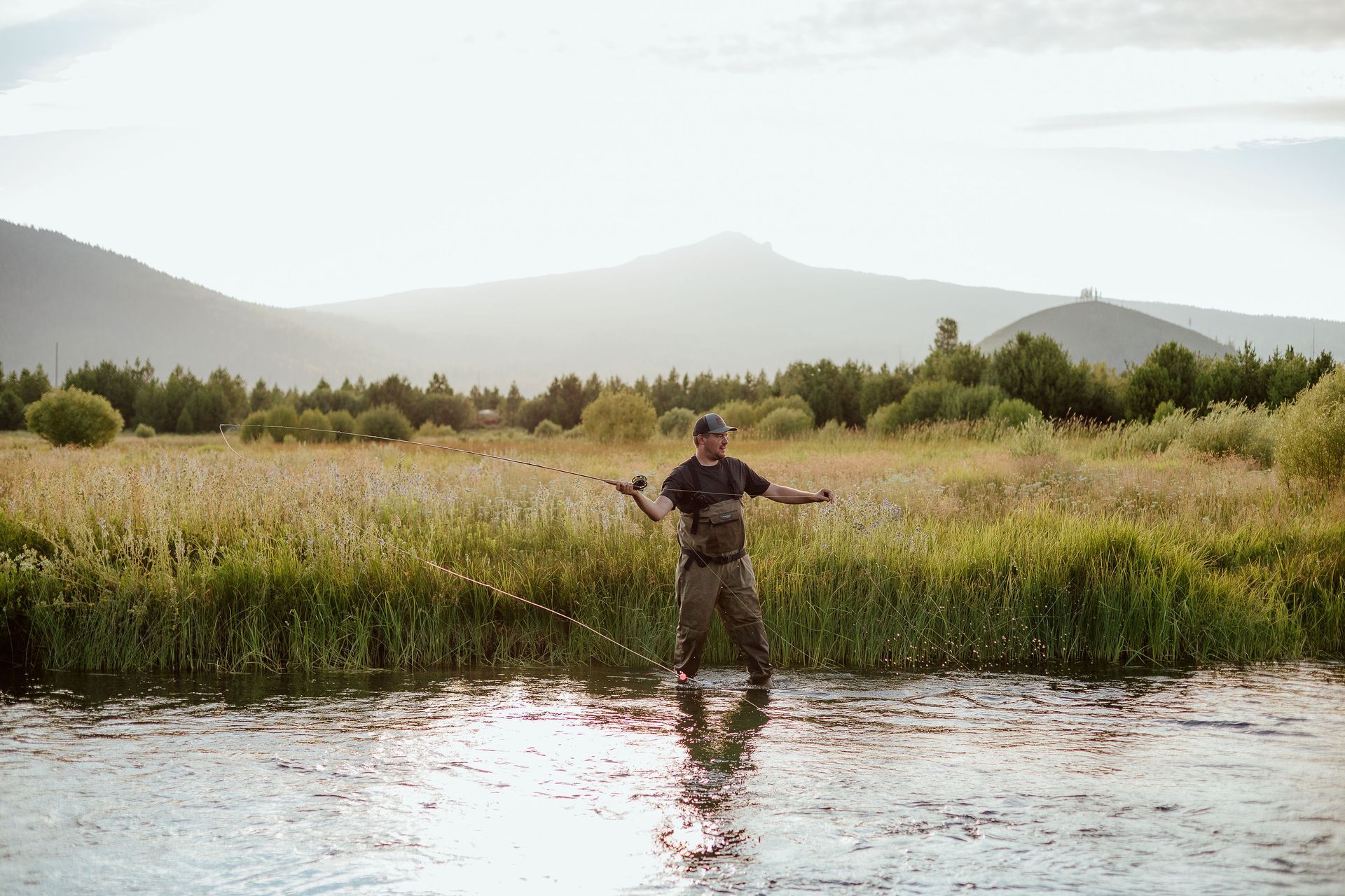 Man fly fishing in Central Oregon with views of the Cascades