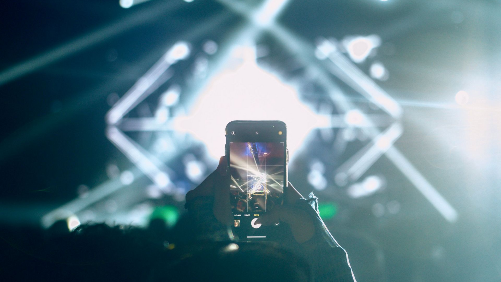 person taking a picture of the stage during a concert at Hayden Homes Amphitheater in Bend