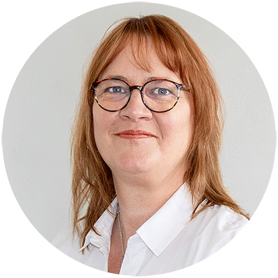 Eine Frau in einer weißen Bluse, lächelnd.