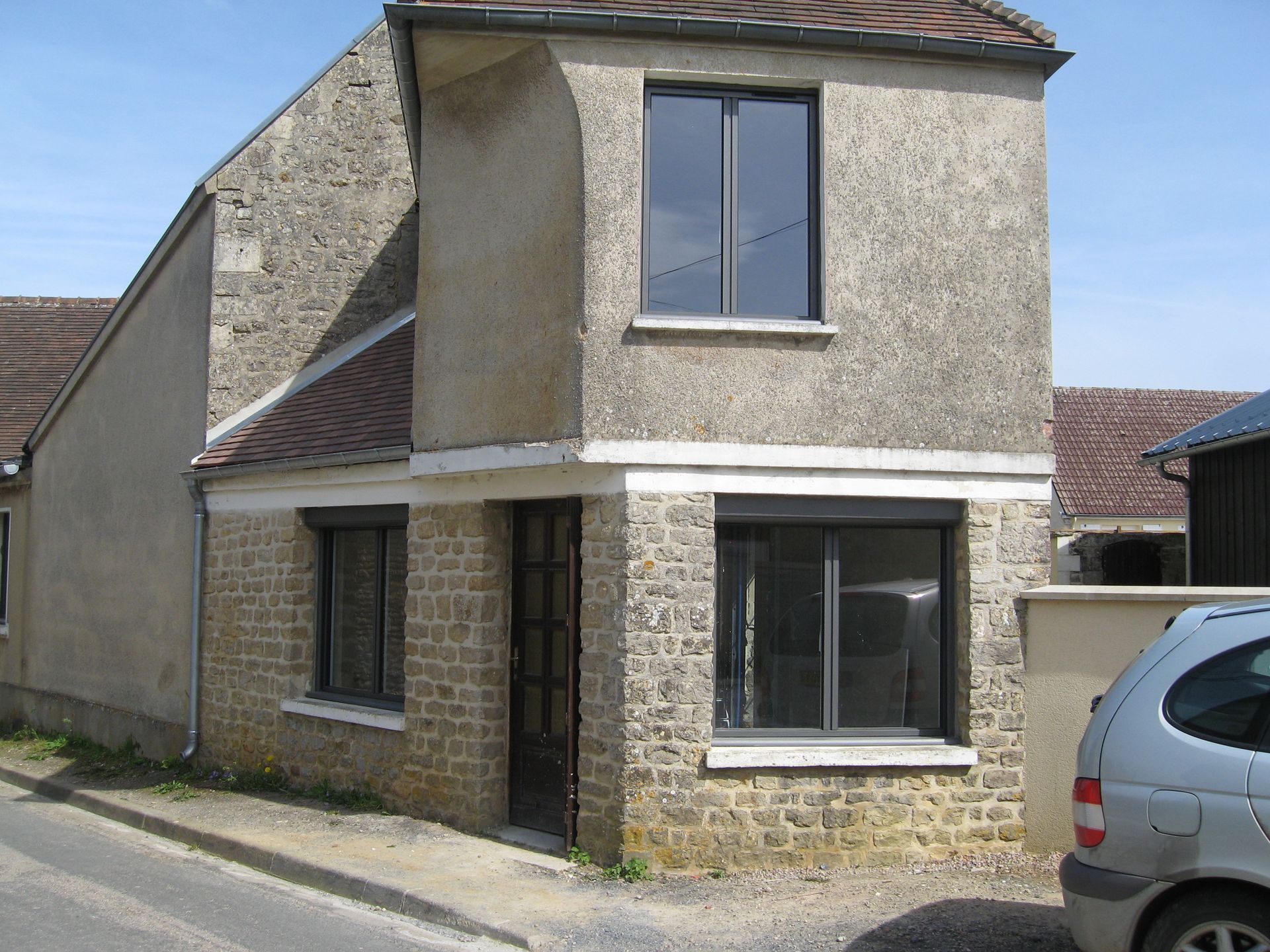 Fenêtres et porte sur une façade en pierre.
