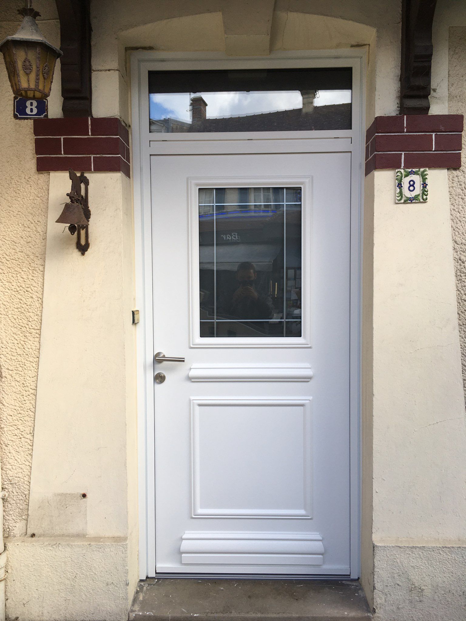 Porte d'entrée en PVC blanc avec une vitre carrée.