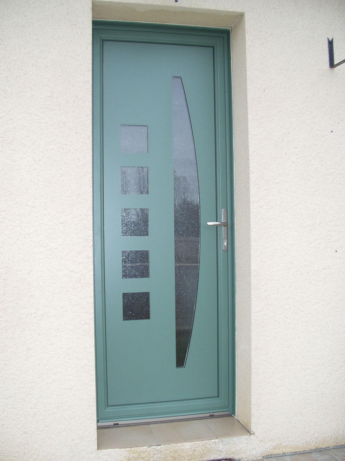 Porte verte avec des petits éléments vitrés.