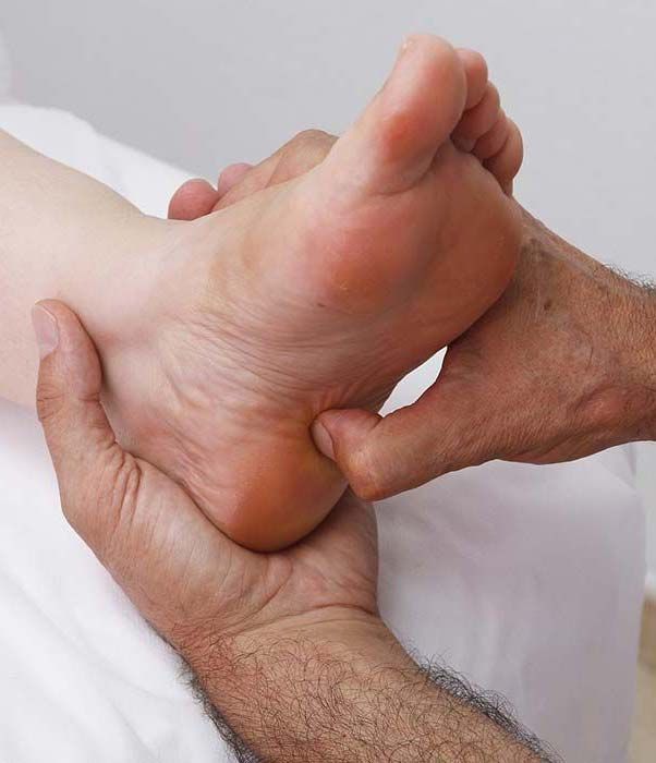 Manos masajeando un pie; primer plano de la planta y el talón sostenidos y presionados.