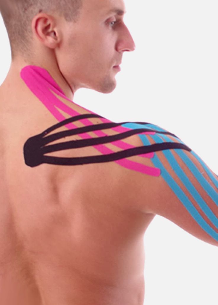 Hombro y brazo de un hombre con cinta kinesiológica de colores aplicada como soporte. Cinta rosa, azul y negra visibles.