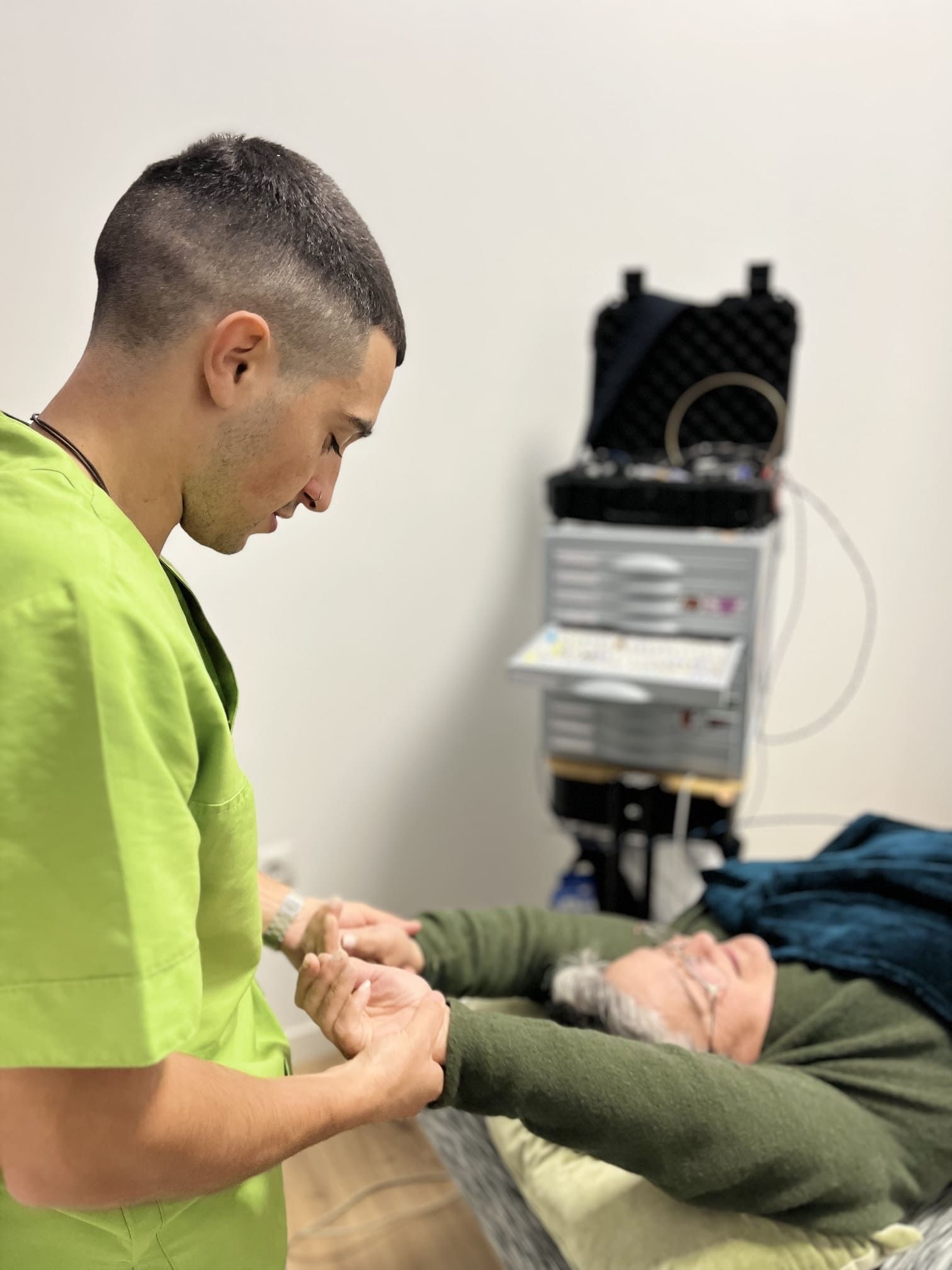 Un hombre con un uniforme verde habla con un hombre mayor que está acostado en una cama.