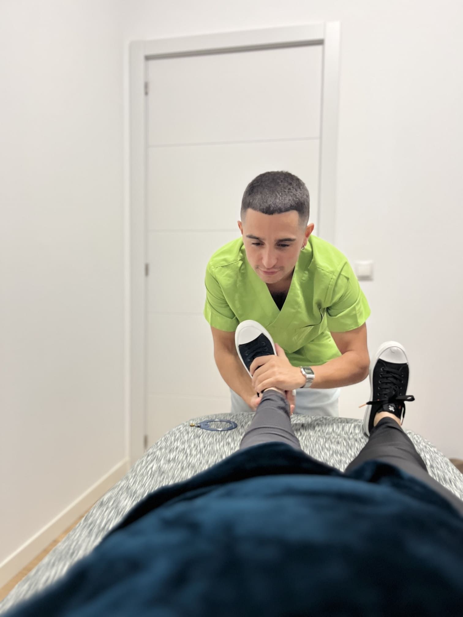 Un hombre con un matorral verde está estirando la pierna de una persona.
