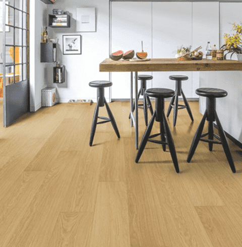 Una cocina con mesa y taburetes de madera y suelo de madera.