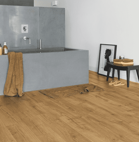 Un baño con bañera y suelo de madera.