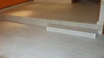 Un piso de baldosas blancas con escaleras que conducen a una habitación.