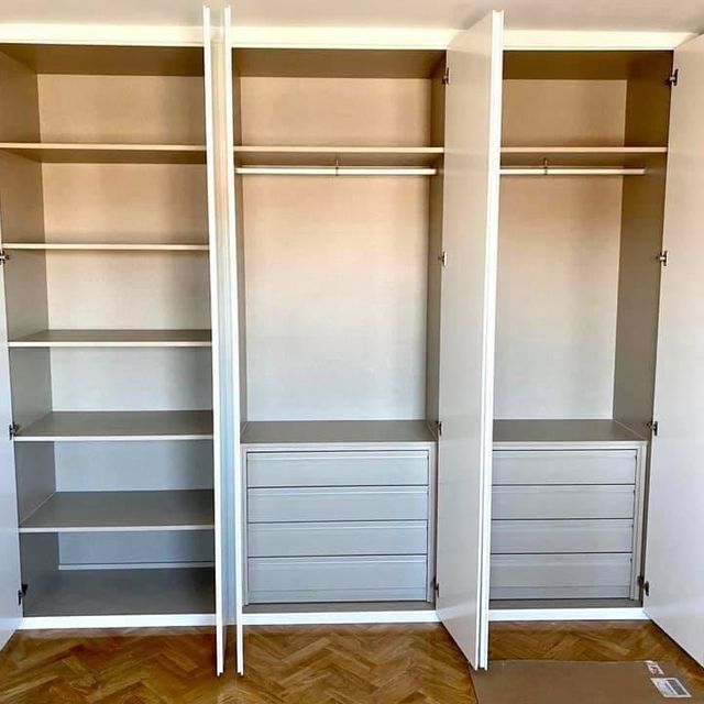 Un armario vacío con las puertas abiertas y estantes y cajones.