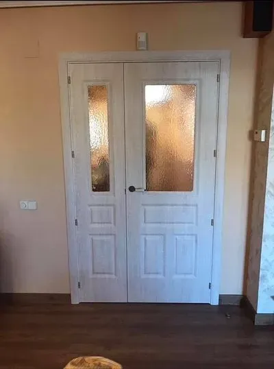 Un par de puertas dobles blancas con vidrio en una sala de estar.
