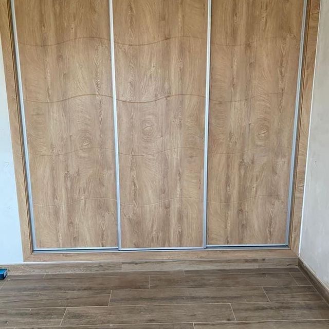 Un armario de madera con puertas correderas en una habitación con suelo de baldosas.