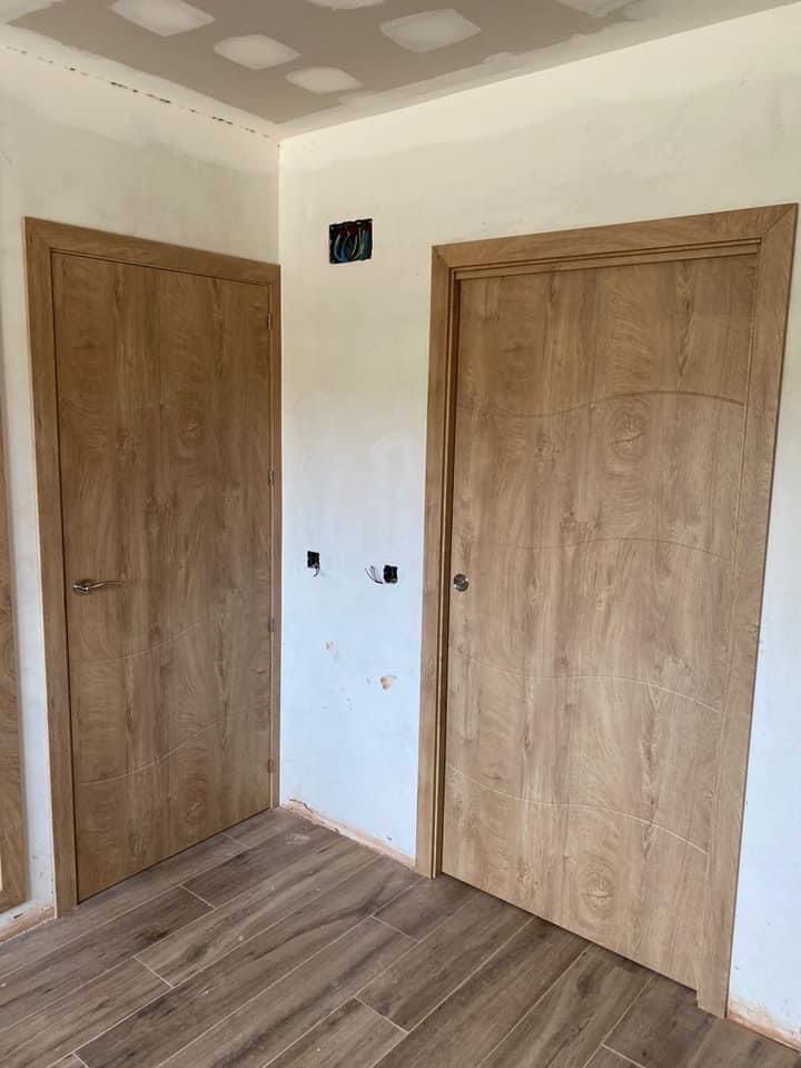 Una habitación con dos puertas de madera y suelo de baldosas.