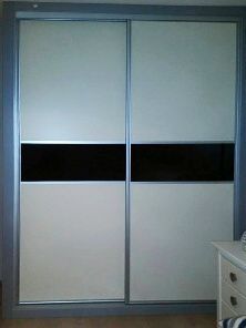 Un armario corredizo blanco y negro con una raya negra en la puerta en un dormitorio.