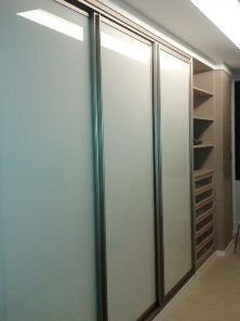 Un vestidor con puertas corredizas de vidrio y estantes.