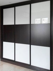 Un armario con puertas corredizas de vidrio en blanco y negro en un dormitorio.