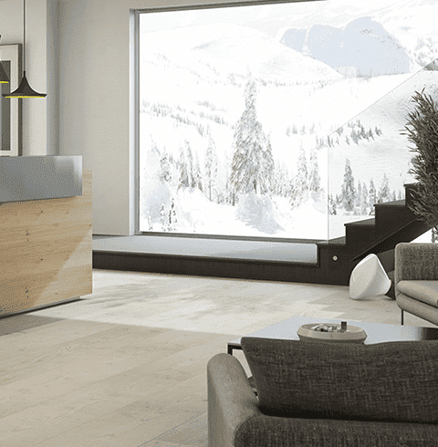 Una sala de estar con un sofá, escaleras y una gran ventana con vista a una montaña nevada.