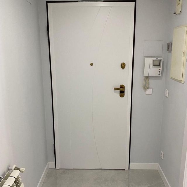 Una puerta blanca está en un pasillo al lado de un teléfono.