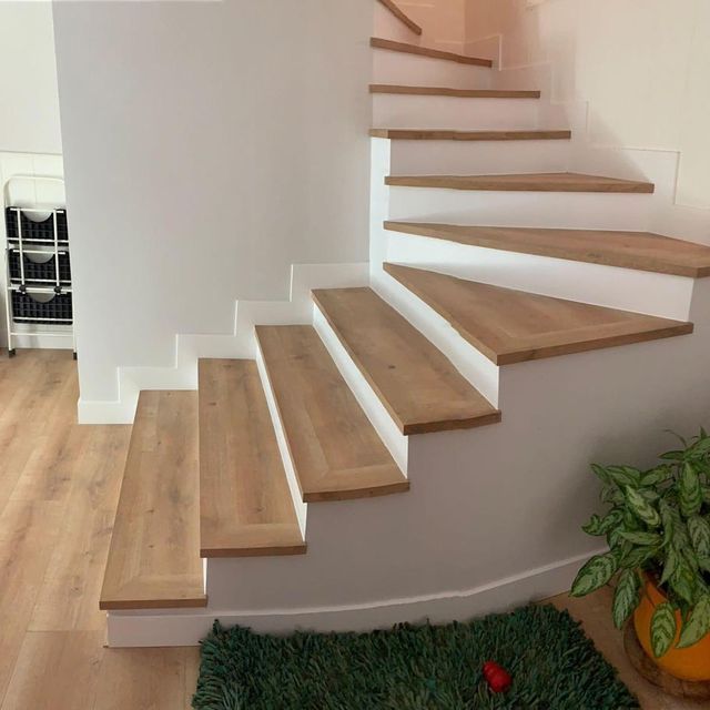 Una escalera con escalones de madera y paredes blancas.