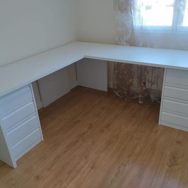 Un escritorio blanco con cajones y una ventana en una habitación.