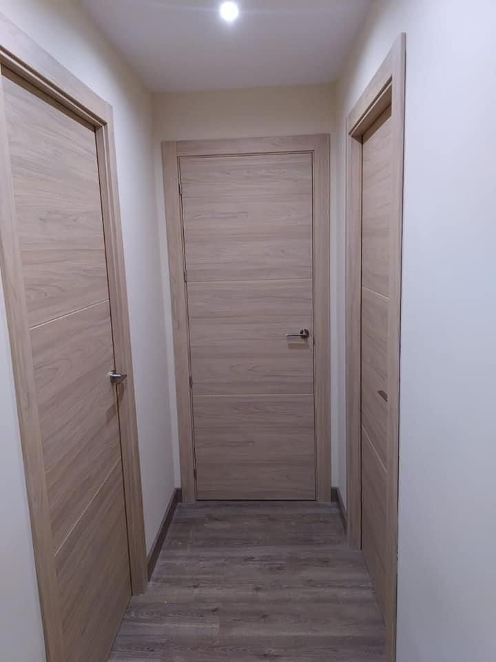 Un pasillo con dos puertas de madera y suelo de madera.