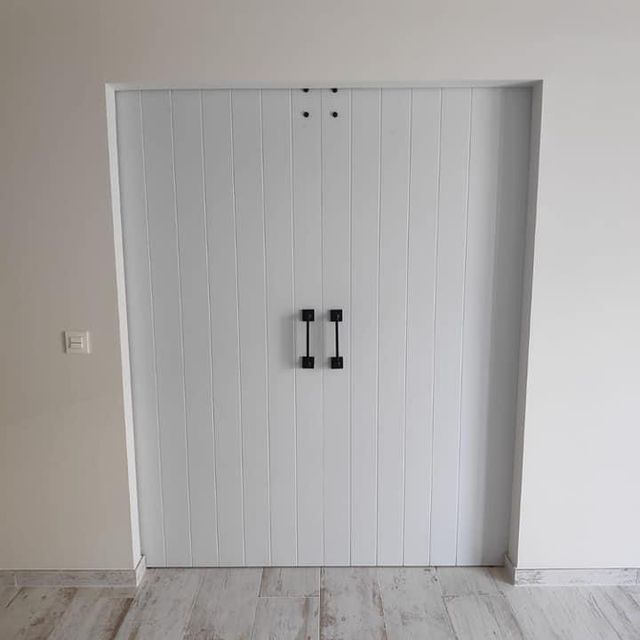 Un par de puertas blancas con manijas negras en una habitación.