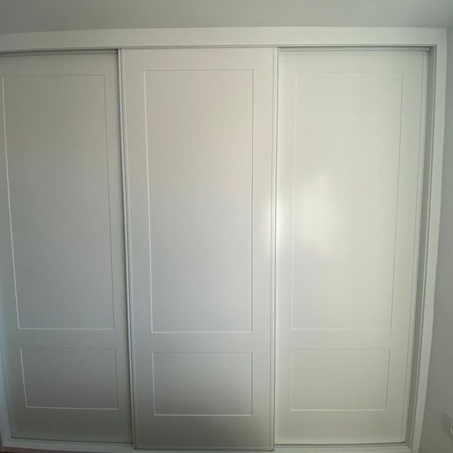 Un armario blanco con puertas correderas en un dormitorio.